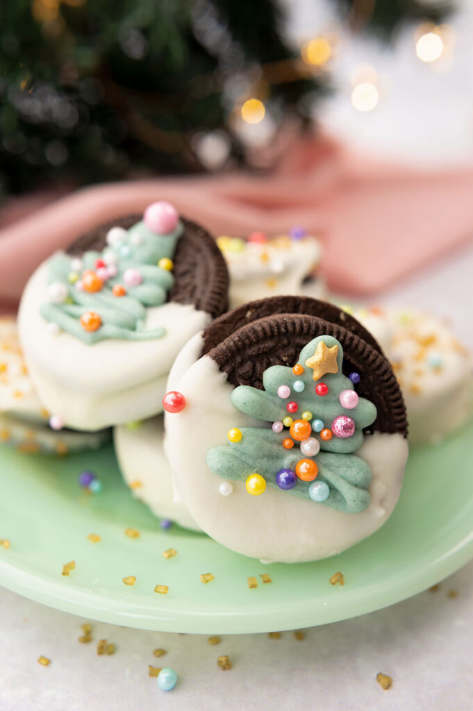 oreo cookies dipped in chocolate and decorated with a piped Christmas tree and sprinkles