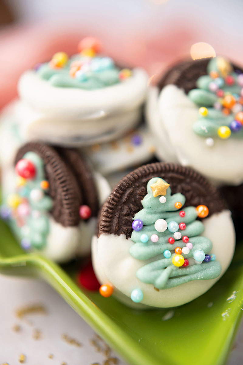 oreo cookies dipped in chocolate and decorated with a piped Christmas tree and sprinkles