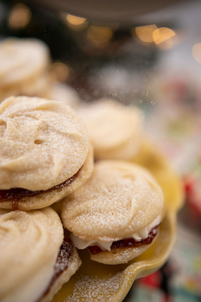 a plate of sandwich cookies topped with powdered sugar