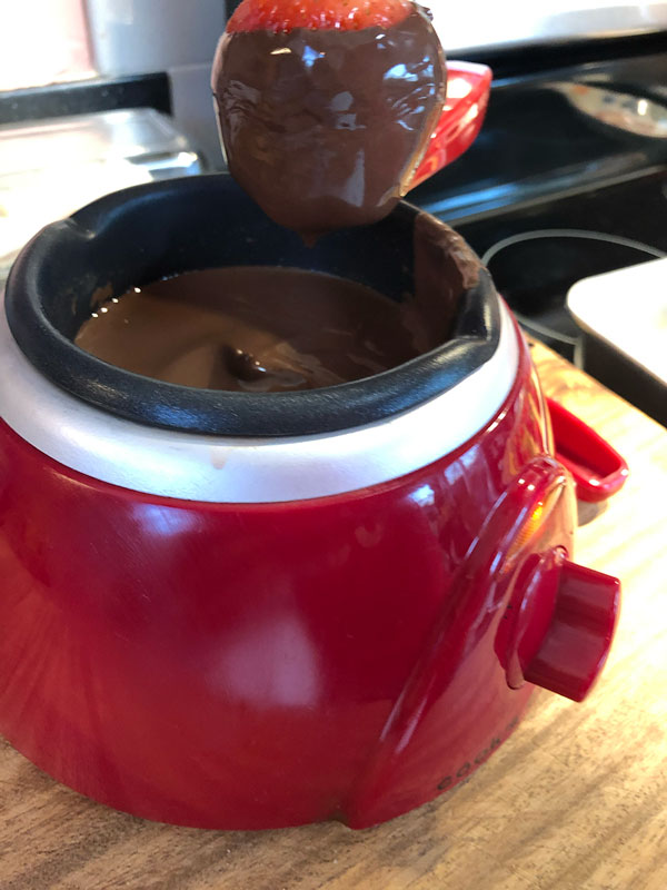 draining excess chocolate from a dipped strawberry