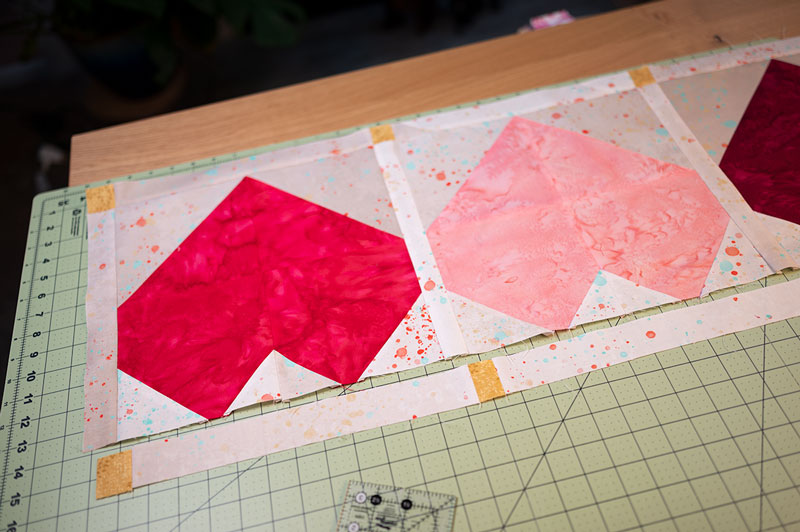 quilt top showing how to piece remaining sash of the joyful hearts table runner