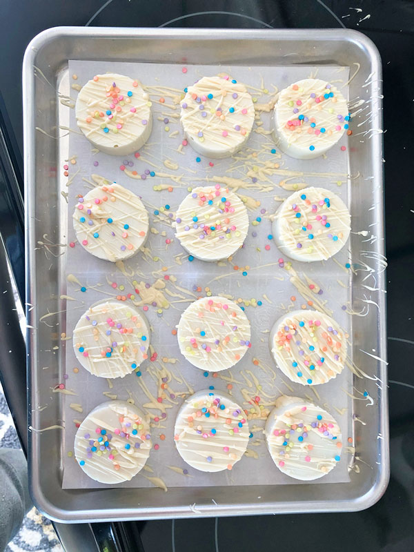 overhead picture of a silver tray with 12 white chocolate dipped cookies decorated with sprinkles
