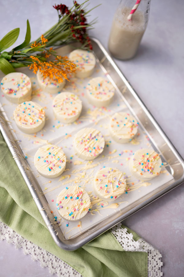 overhead picture of a silver tray with 12 white chocolate dipped cookies decorated with sprinkles