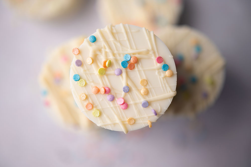 over head picture of white chocolate dipped oreo cookie with colorful sprinkles