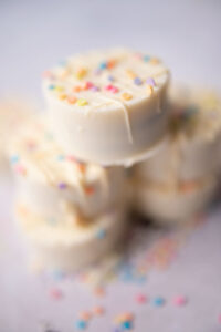 stack of white chocolate dipped Oreo cookies decorated with drizzle and sprinkles