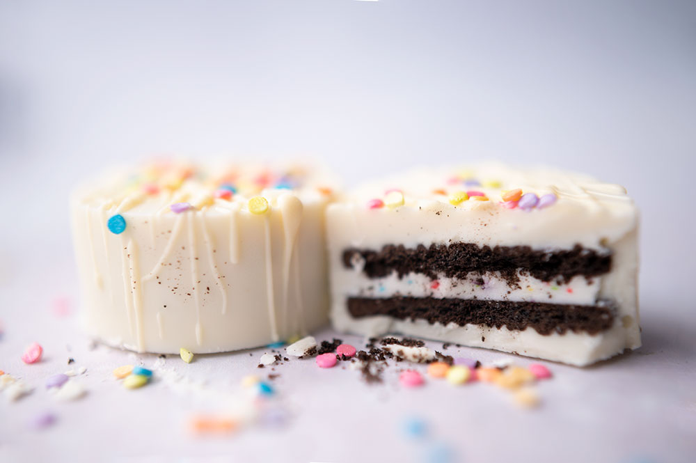 two white chocolate dipped oreos with one cut in half to show the inside