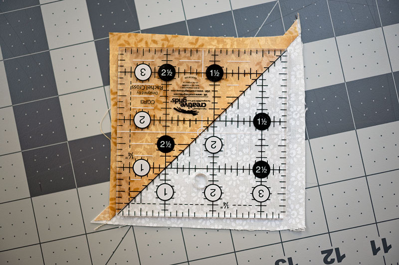 a square ruler overlays an untrimmed HST block