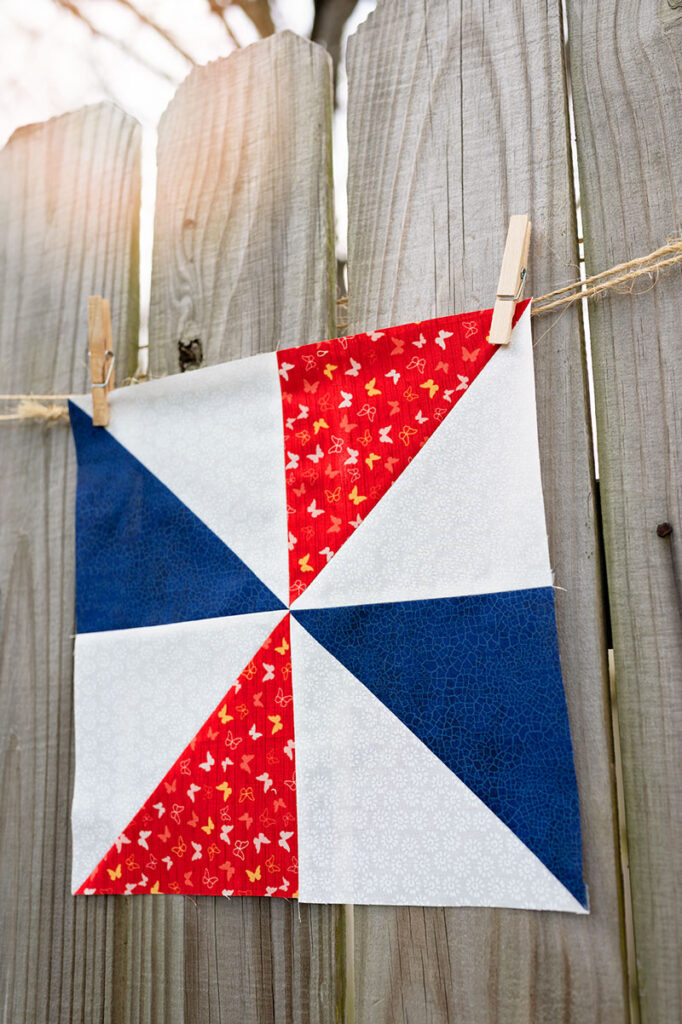 a finished pinwheel block hanging on a fence