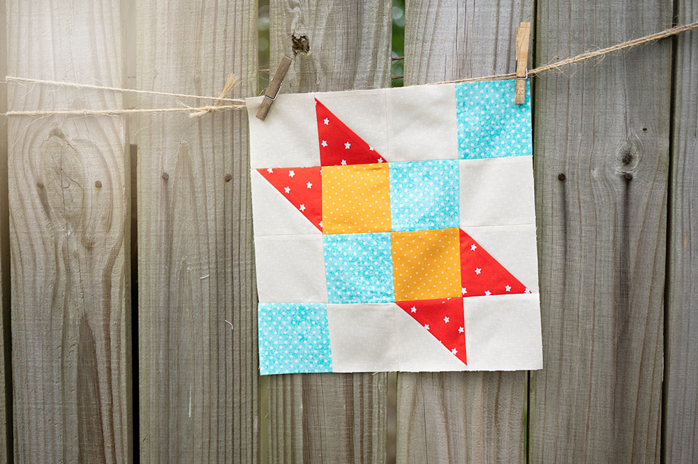 colorful quilt block hanging on a rustic fence