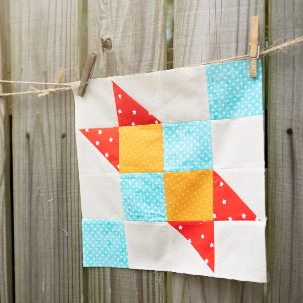 colorful quilt block hanging on a rustic fence