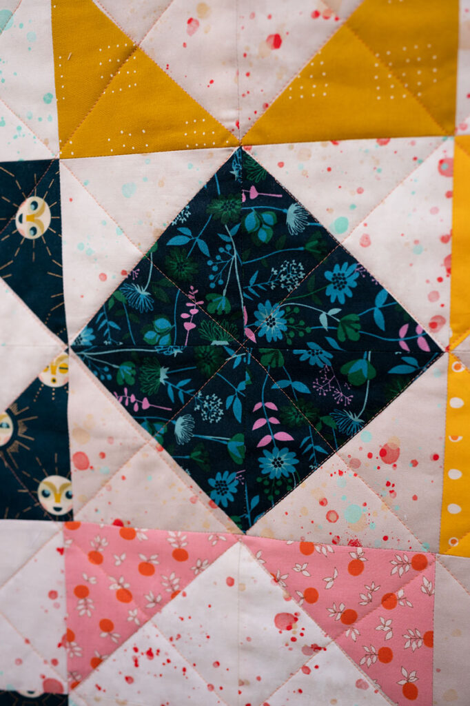 a quilt block with a dark colored diamond in the center