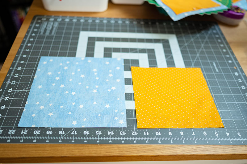 two squares of fabric laying on a cutting mat