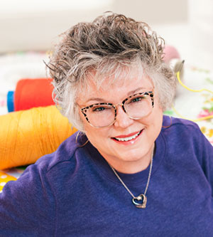 smiling woman wearing glasses in a purple shirt