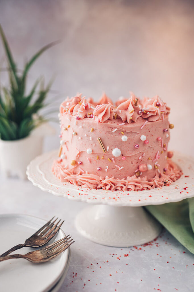 pink strawberry cake on a white cake stand