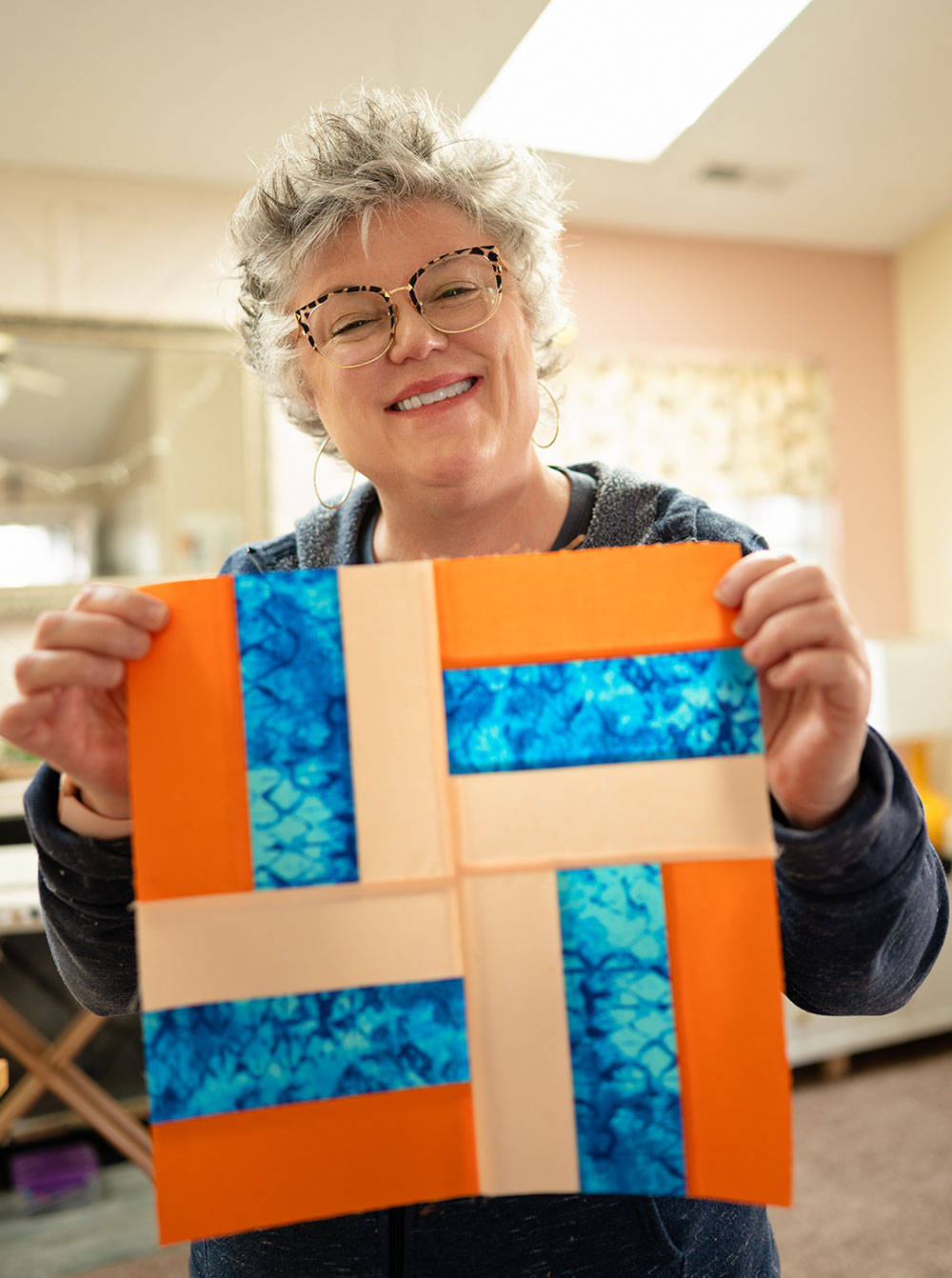 smiling woman holds a rail fence quilt block