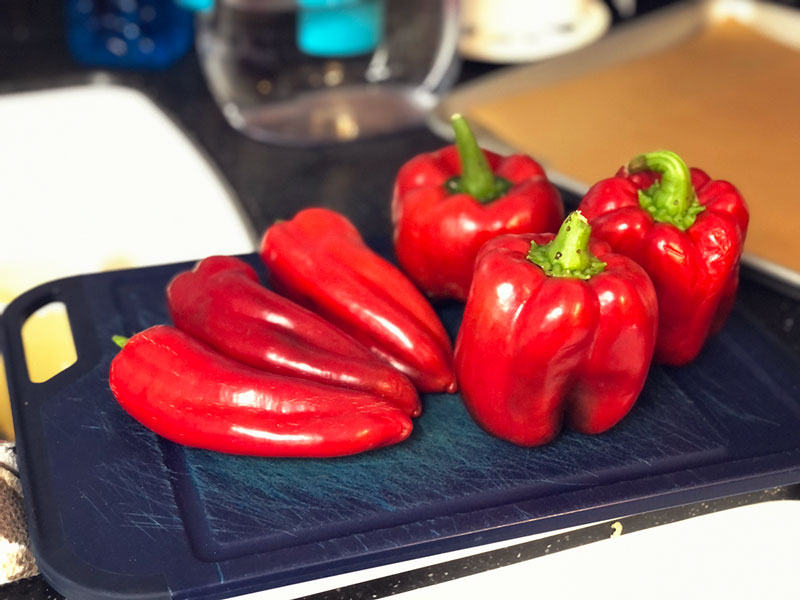 a cutting board full of red sweet peppers