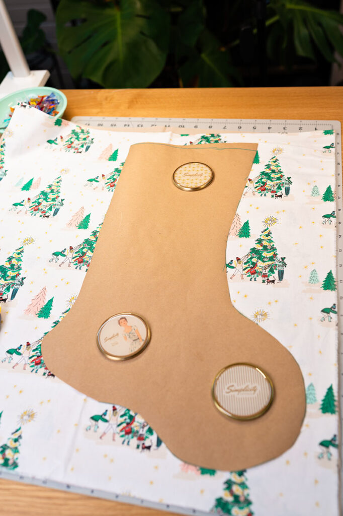 a homemade paper pattern is onto a piece of holiday fabric