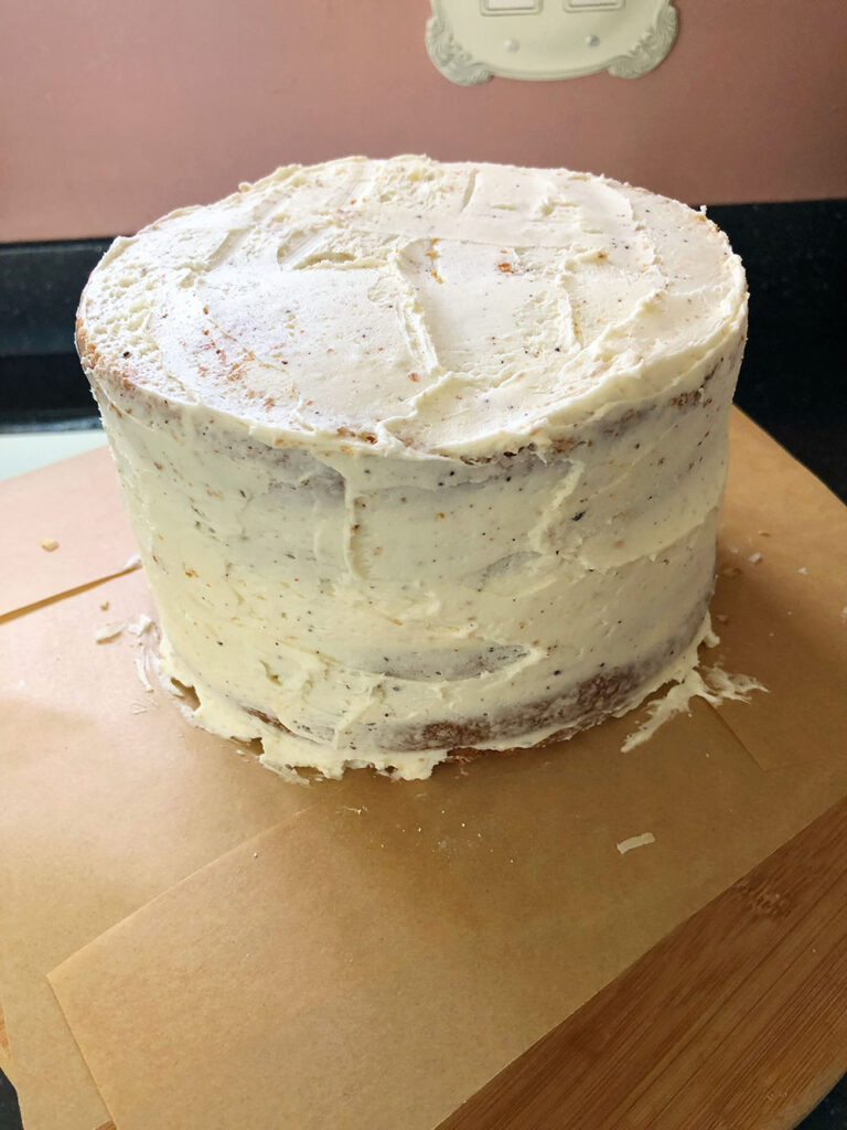 a layer cake is crumb coated in preparation for final decoration