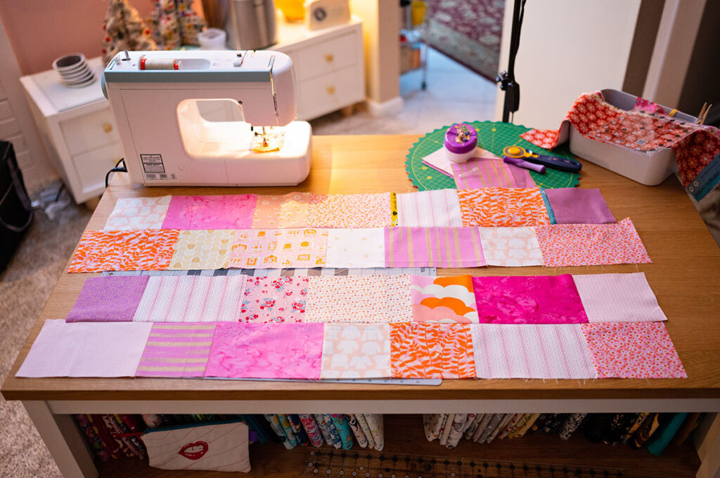 patchwork quilt pieces laid out on top of a sewing table with a sewing machine
