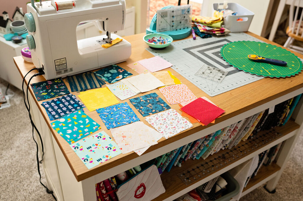 several cut squares of fabric on a sewing table