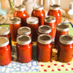 a table full of newly canned tomato sauce in pint jars