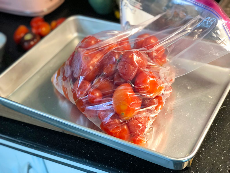 bag of thawed tomatoes on a sheet pan