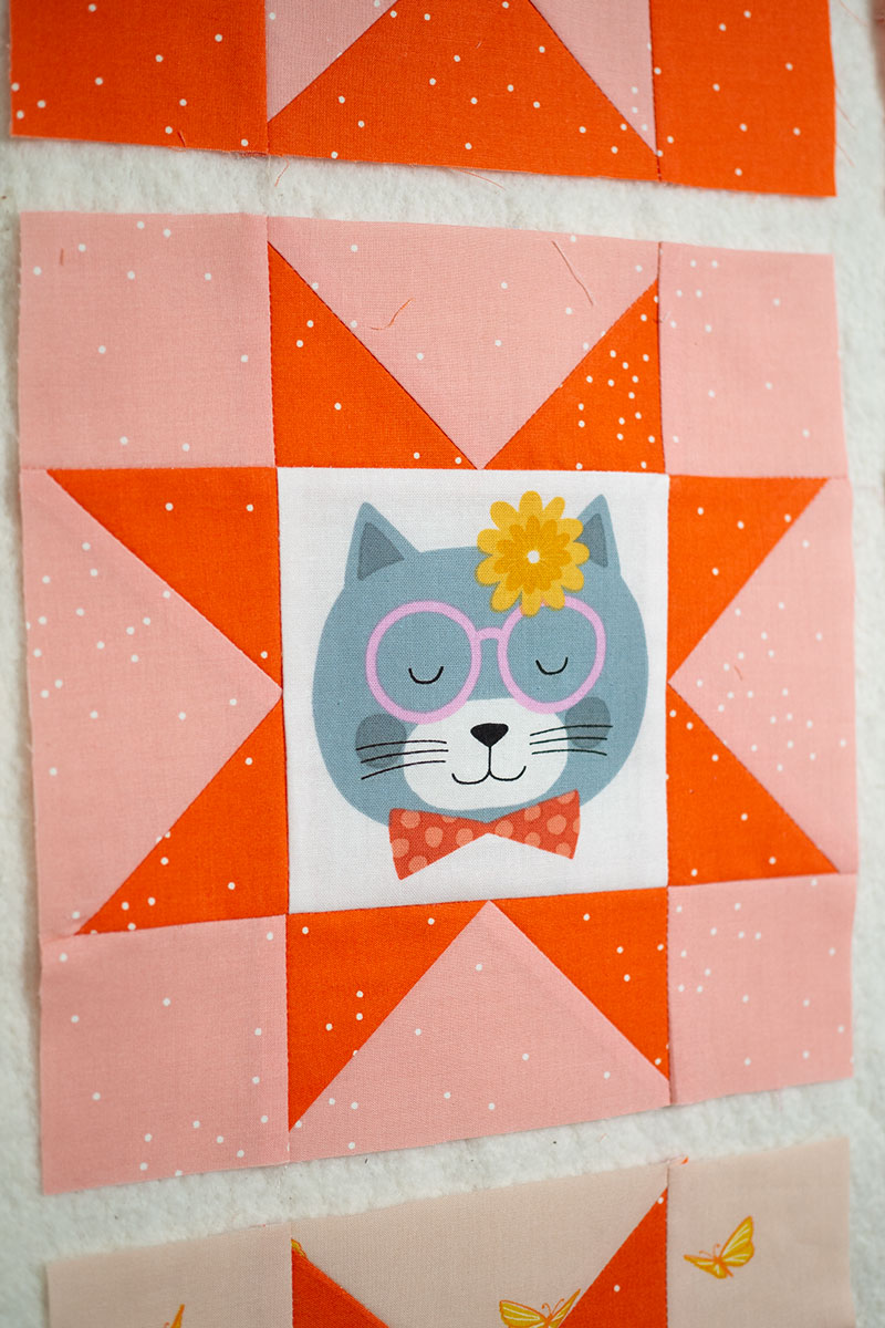 pink and orange sawtooth star quilt block with illustrated cats in the center