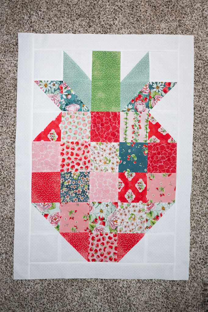 strawberry quilt block completed with a narrow border applied.