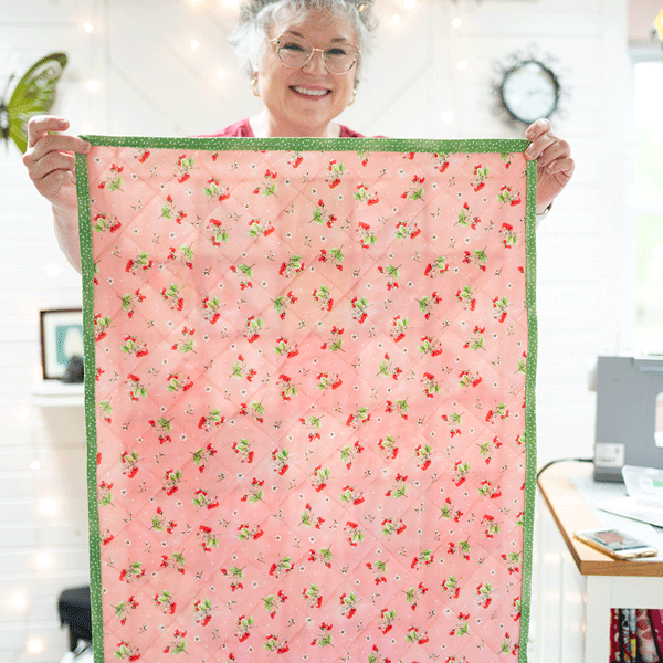 woman showing both sides of a finished wall quilt