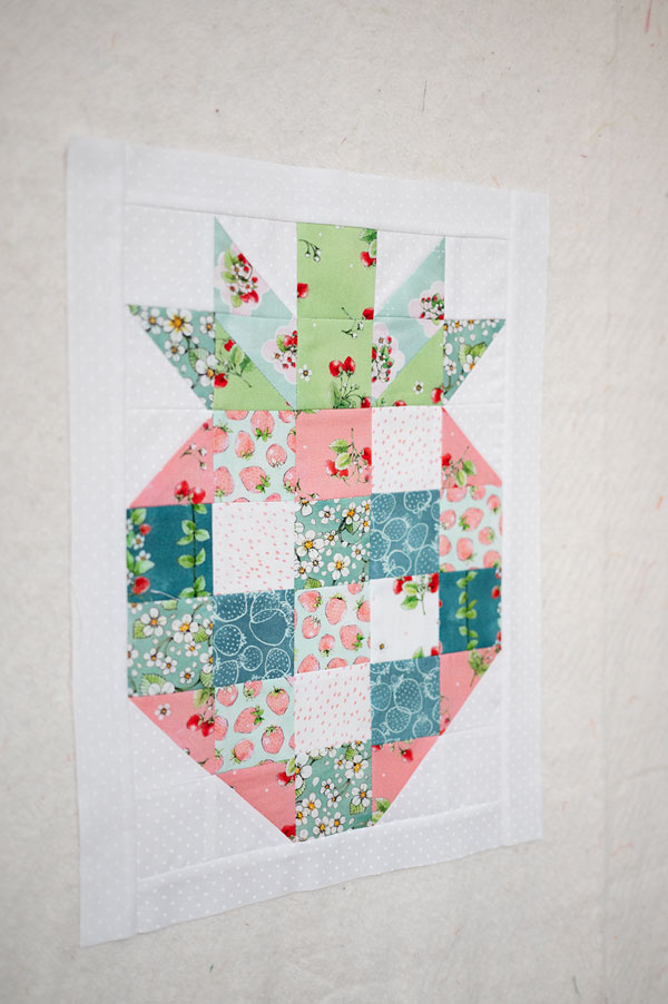 a mini quilt sewn in soft colors as a strawberry motif