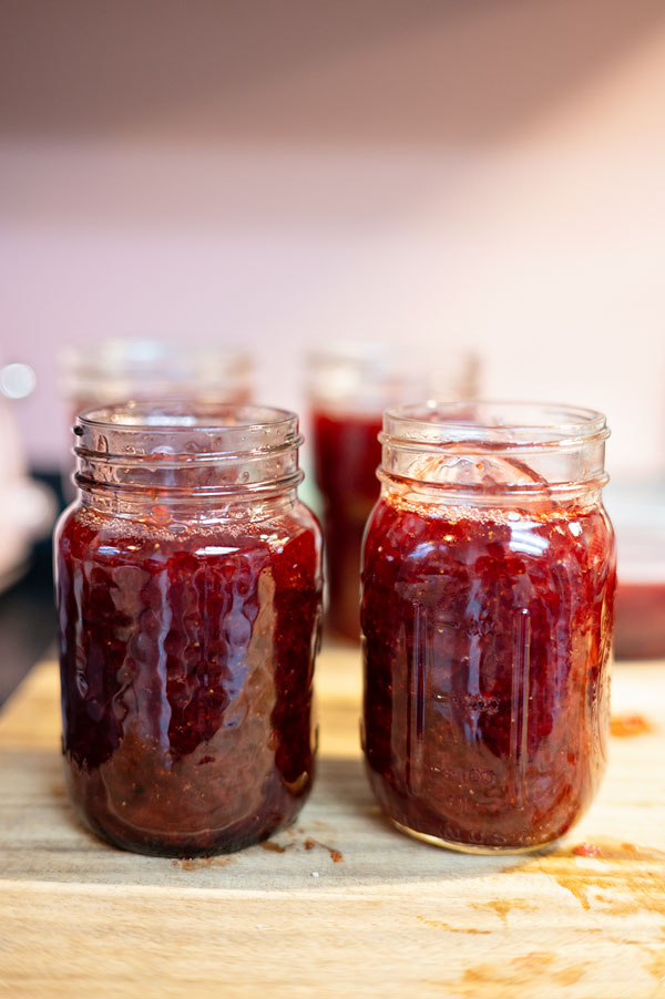 Two pint jars of fresh strawberry jam cooling