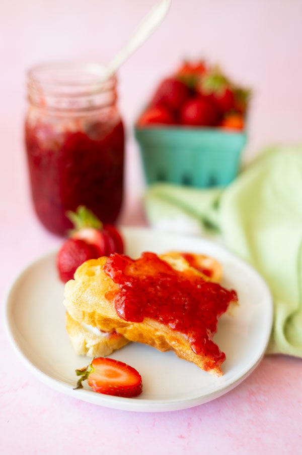 partially eaten toast topped with fresh strawberry jam