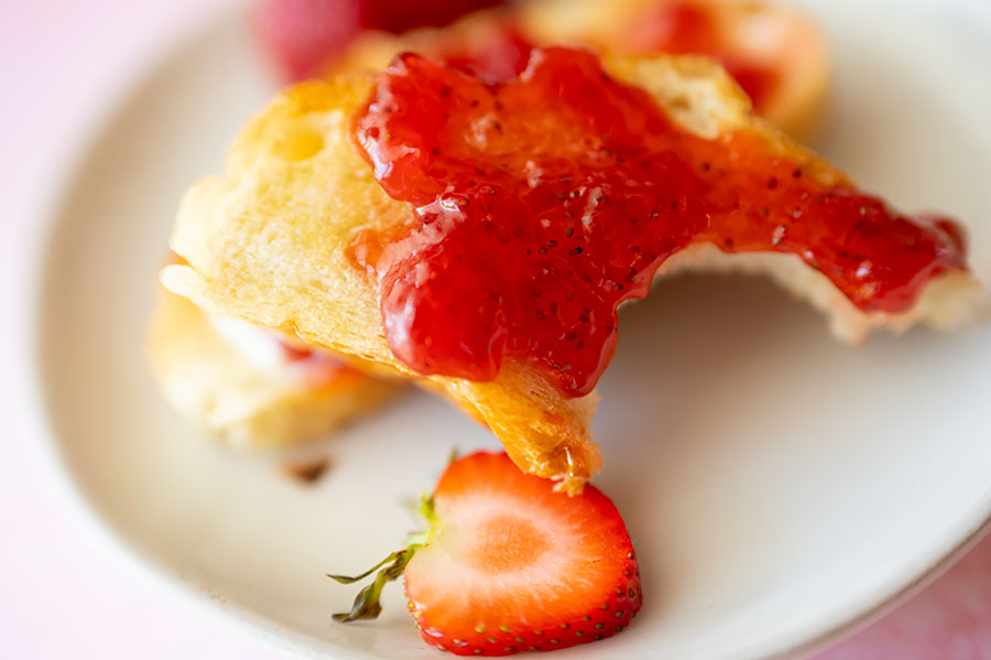 french bread topped with strawberry jam missing a bite