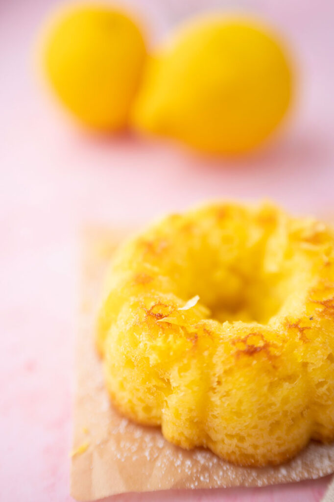 mini bundt style cakes on a pink surface with lemons